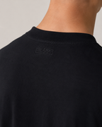 The Standard Fit in Black — Suvin cotton fabric detail on model.